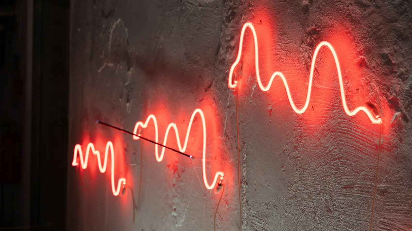 A red neon wavy line glowing on a wall
