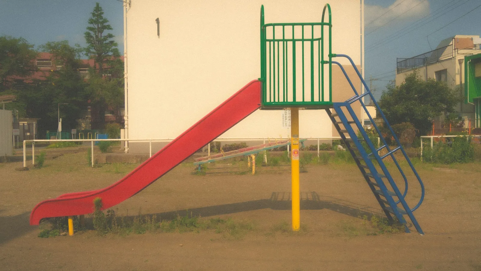 A red playground slide sloping down to the ground