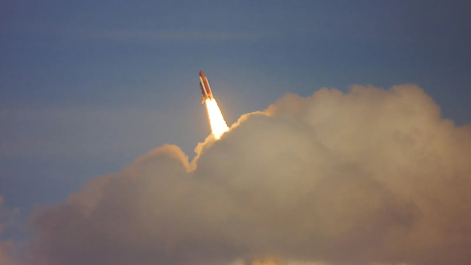 A rocket climbing on a bright flame above clouds of smoke