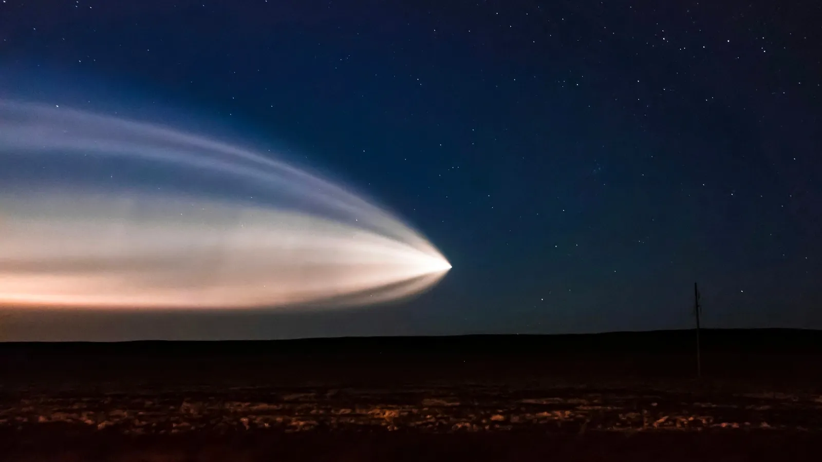 A rocket launch trail glowing across the night sky