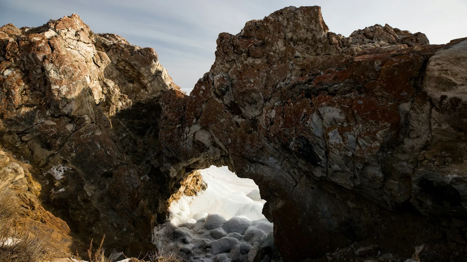 A rocky cave opening against a pale sky