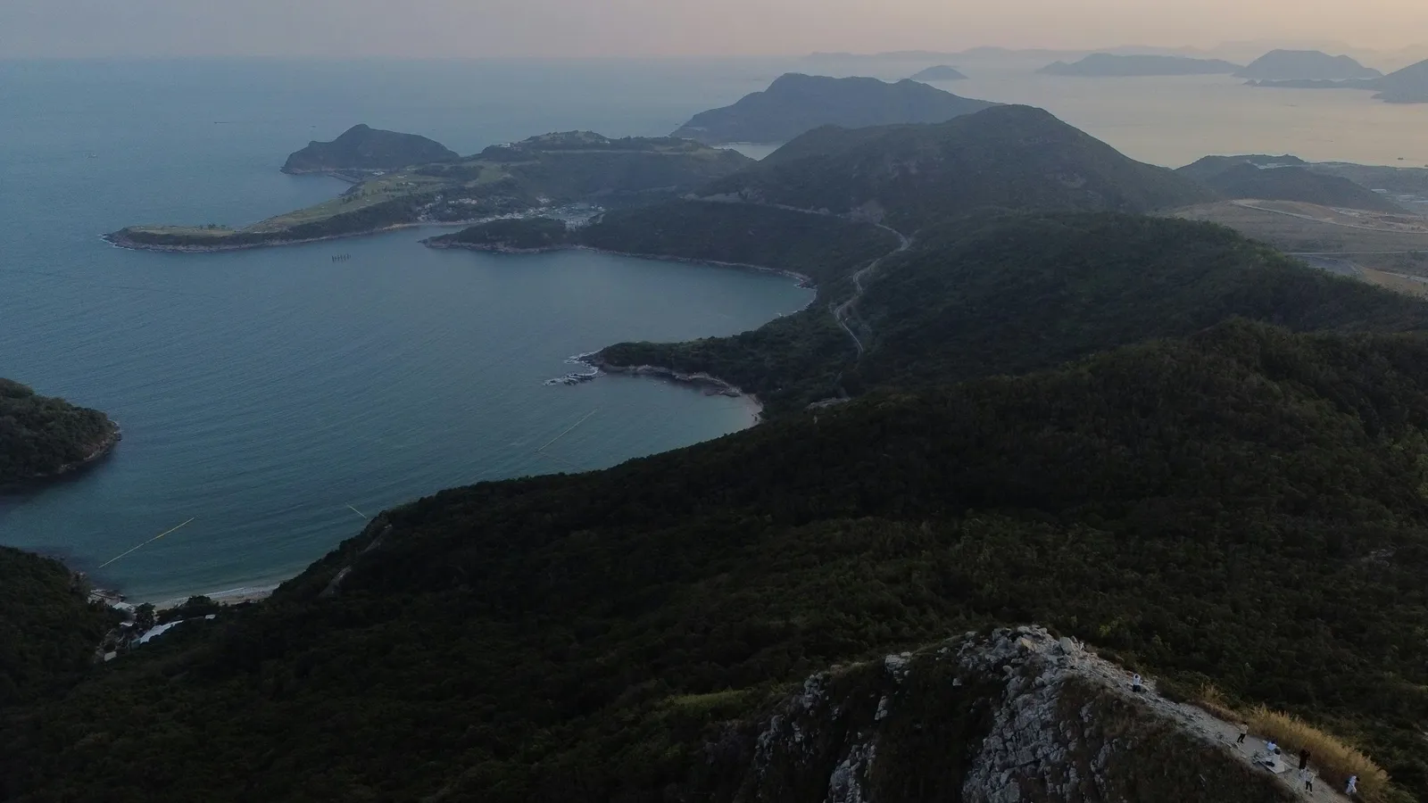A rocky coastline beside a calm sea at dusk