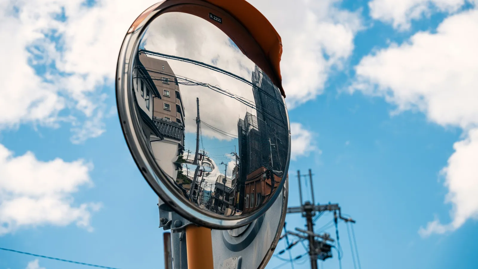 A round convex road mirror against a blue sky
