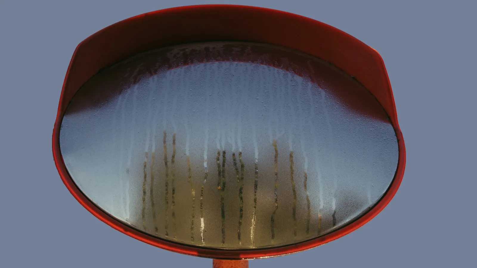A round curved mirror on a red stand