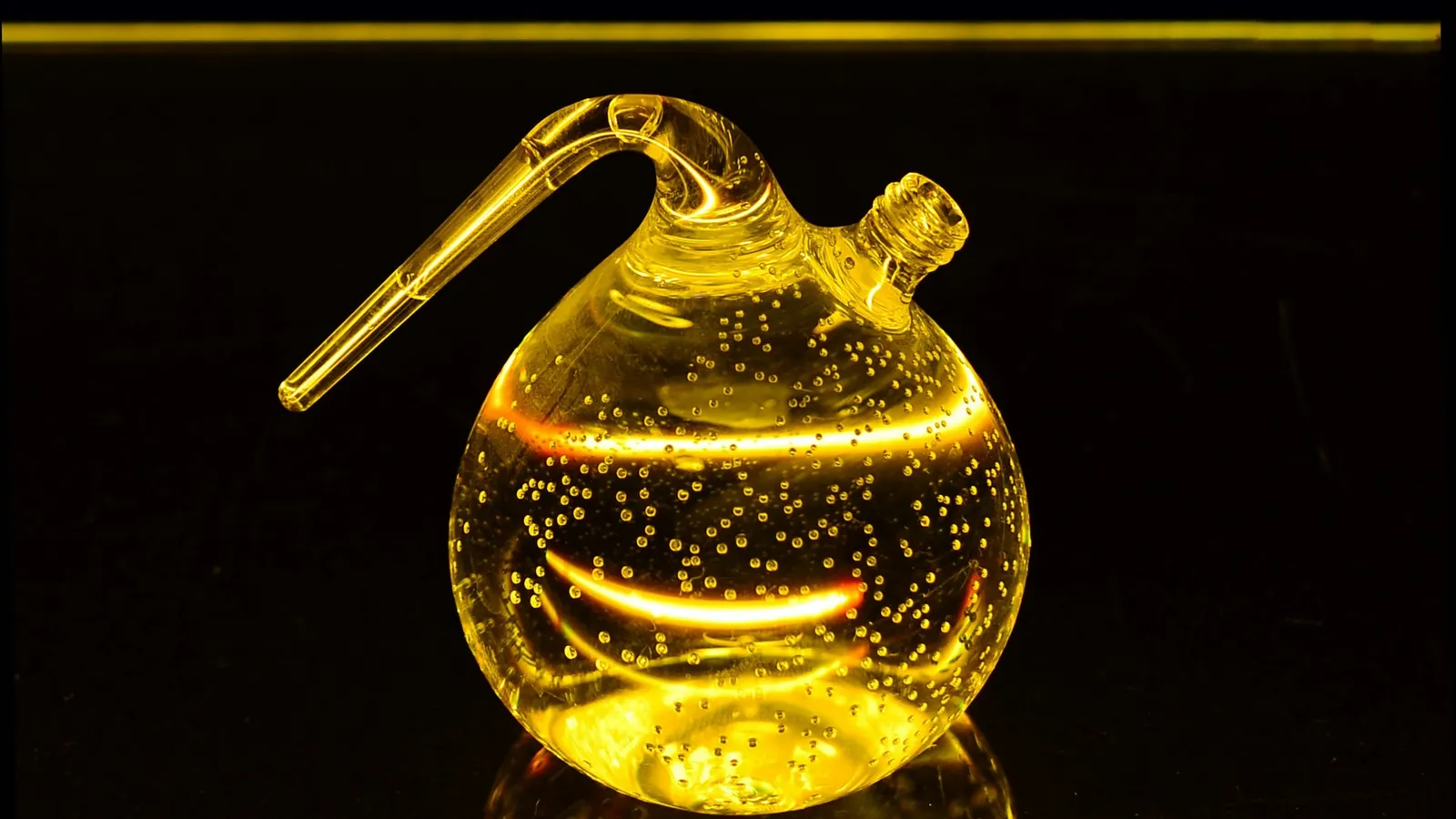 A round glass flask glowing with yellow liquid
