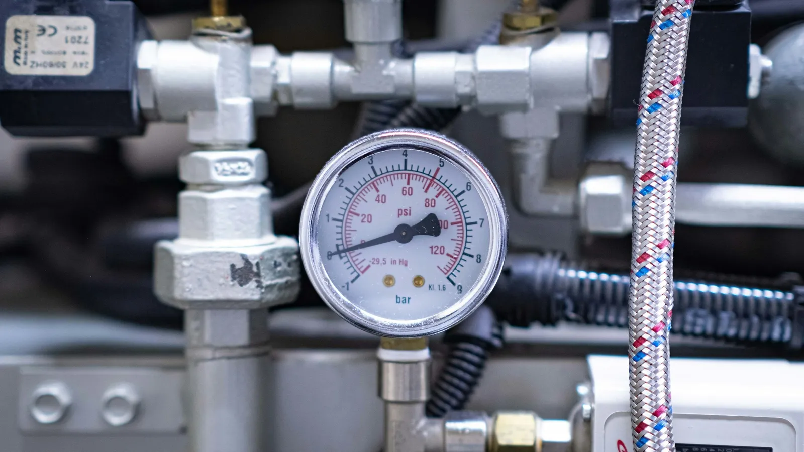 A round pressure gauge mounted on metal gas pipes