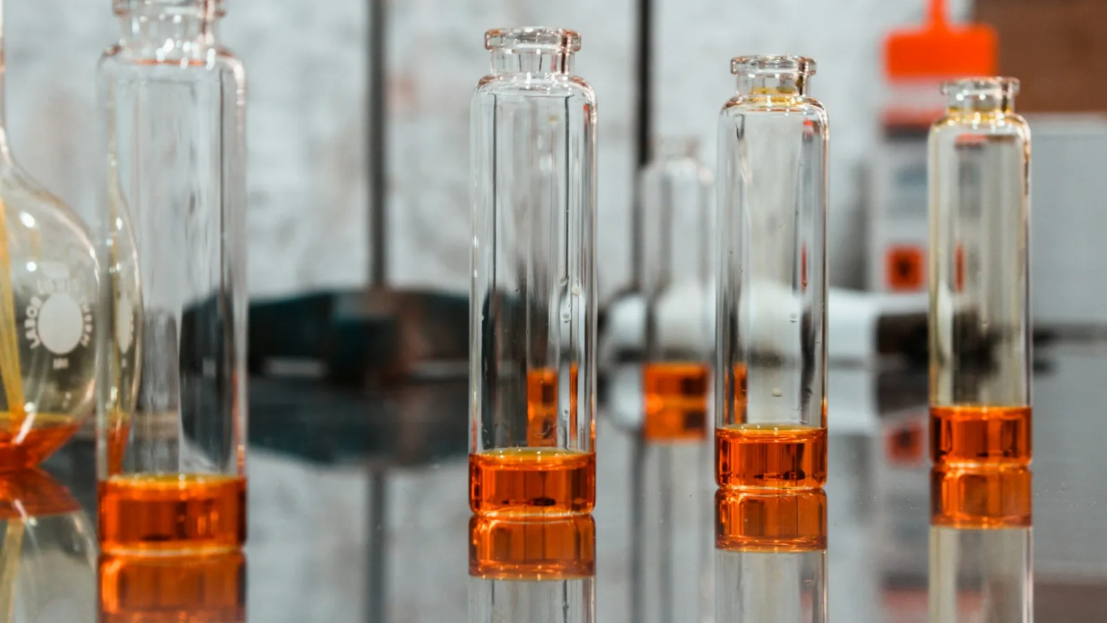 A row of glass flasks containing orange liquid