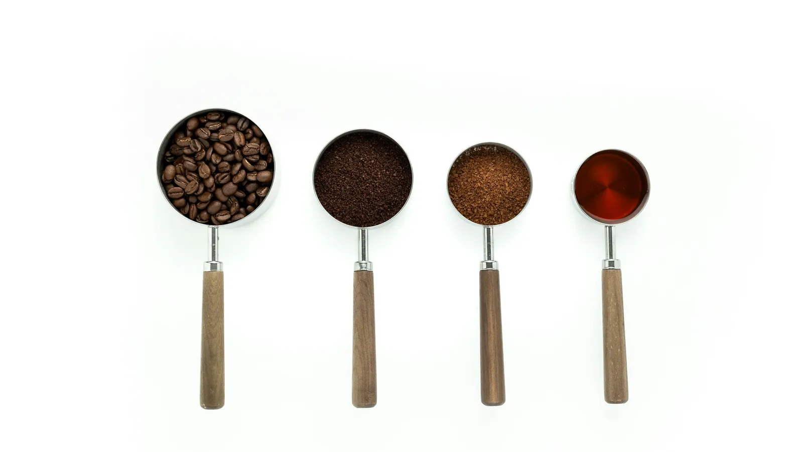 A row of measuring spoons in four sizes filled with spices
