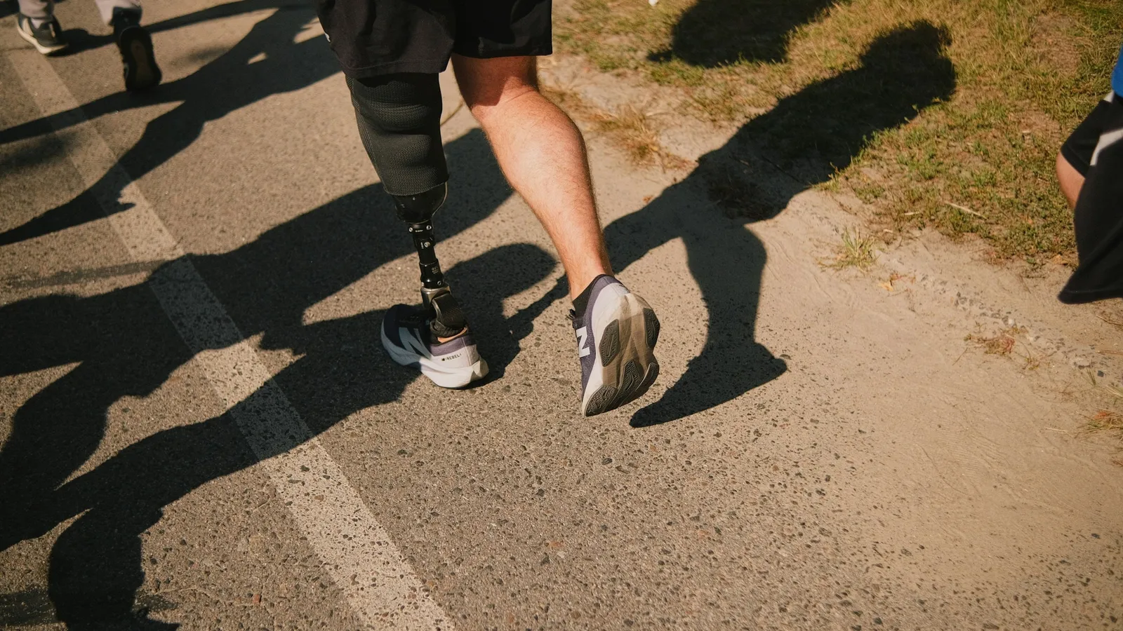 A runner with a prosthetic leg on a sunny road