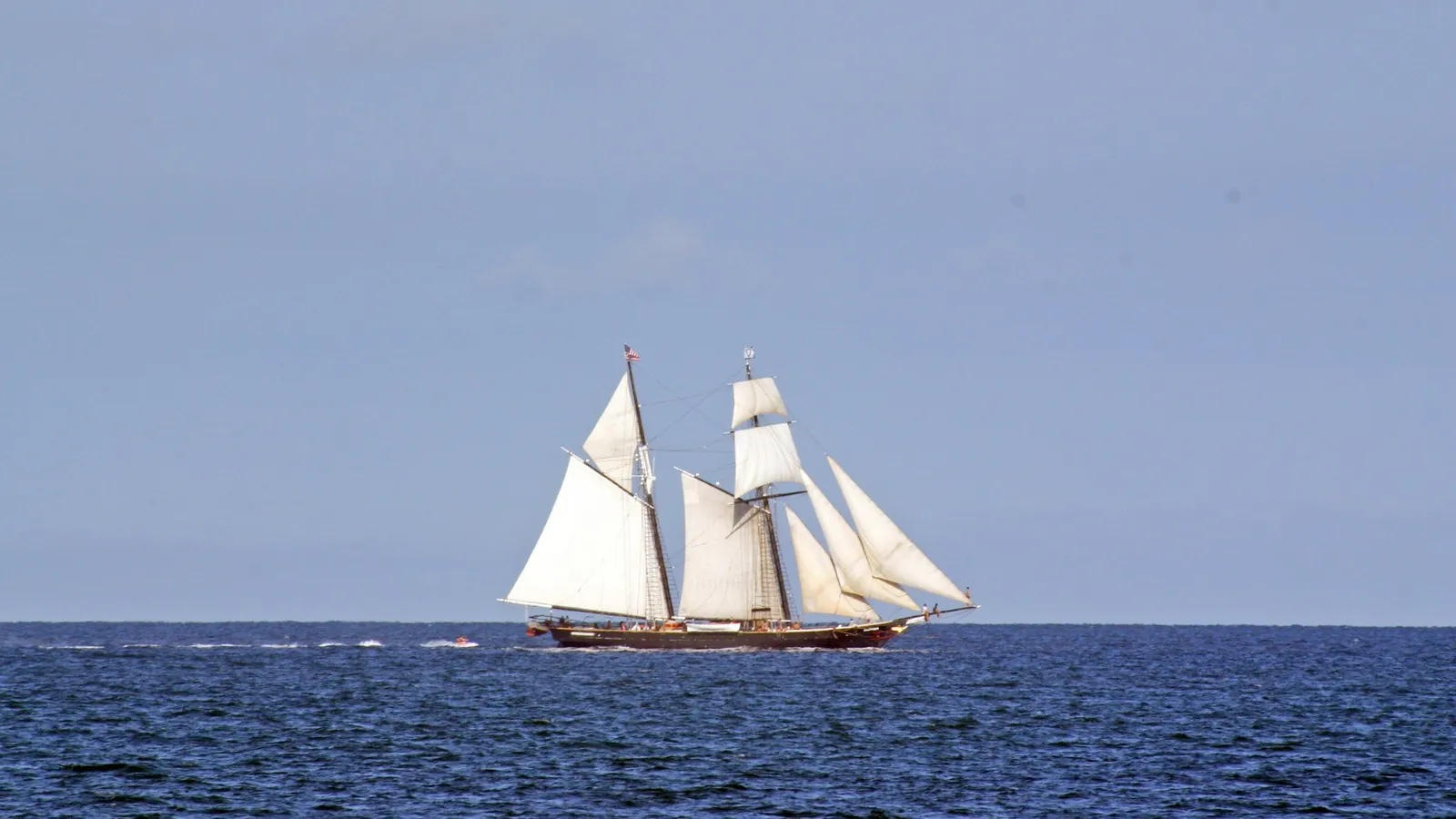A sailing ship with full white sails on open sea