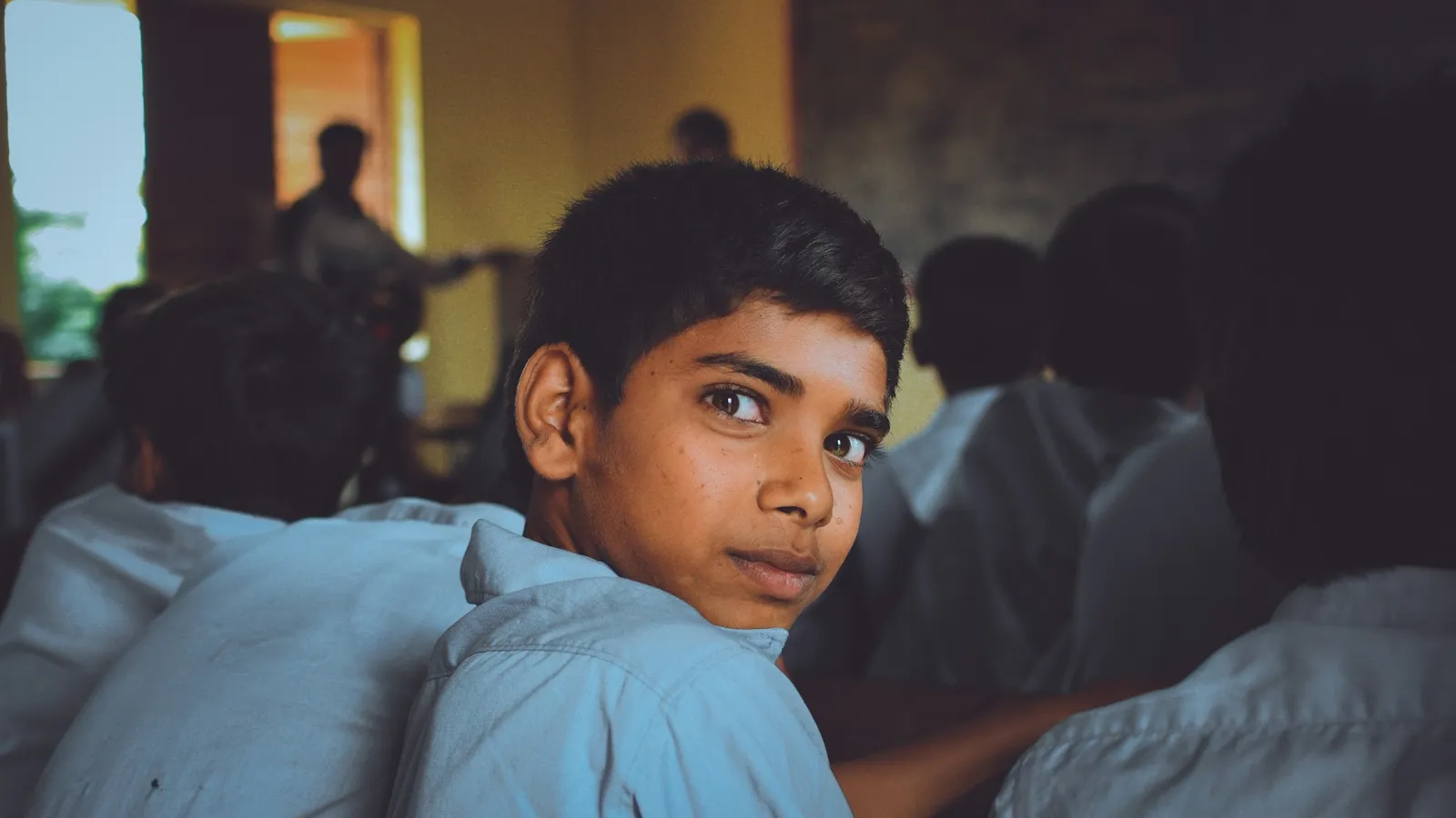 A schoolboy in a classroom looking back over his shoulder