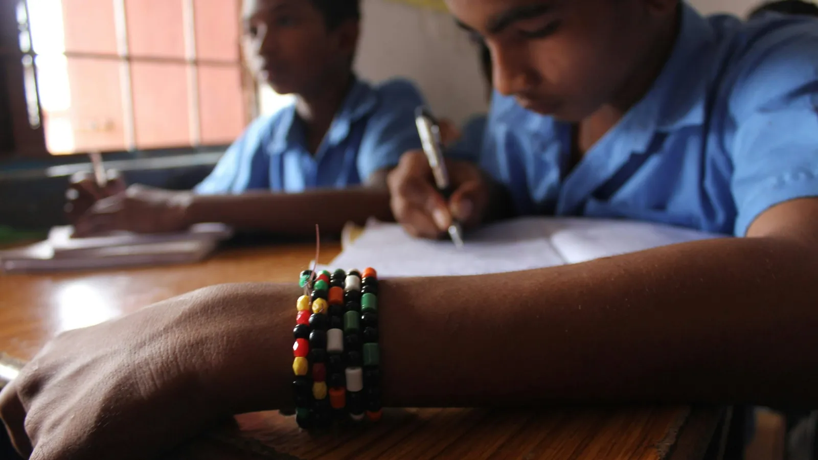 A schoolboy writing at his desk in a classroom