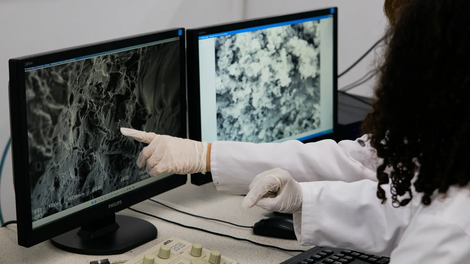 A scientist pointing at cell images on a screen