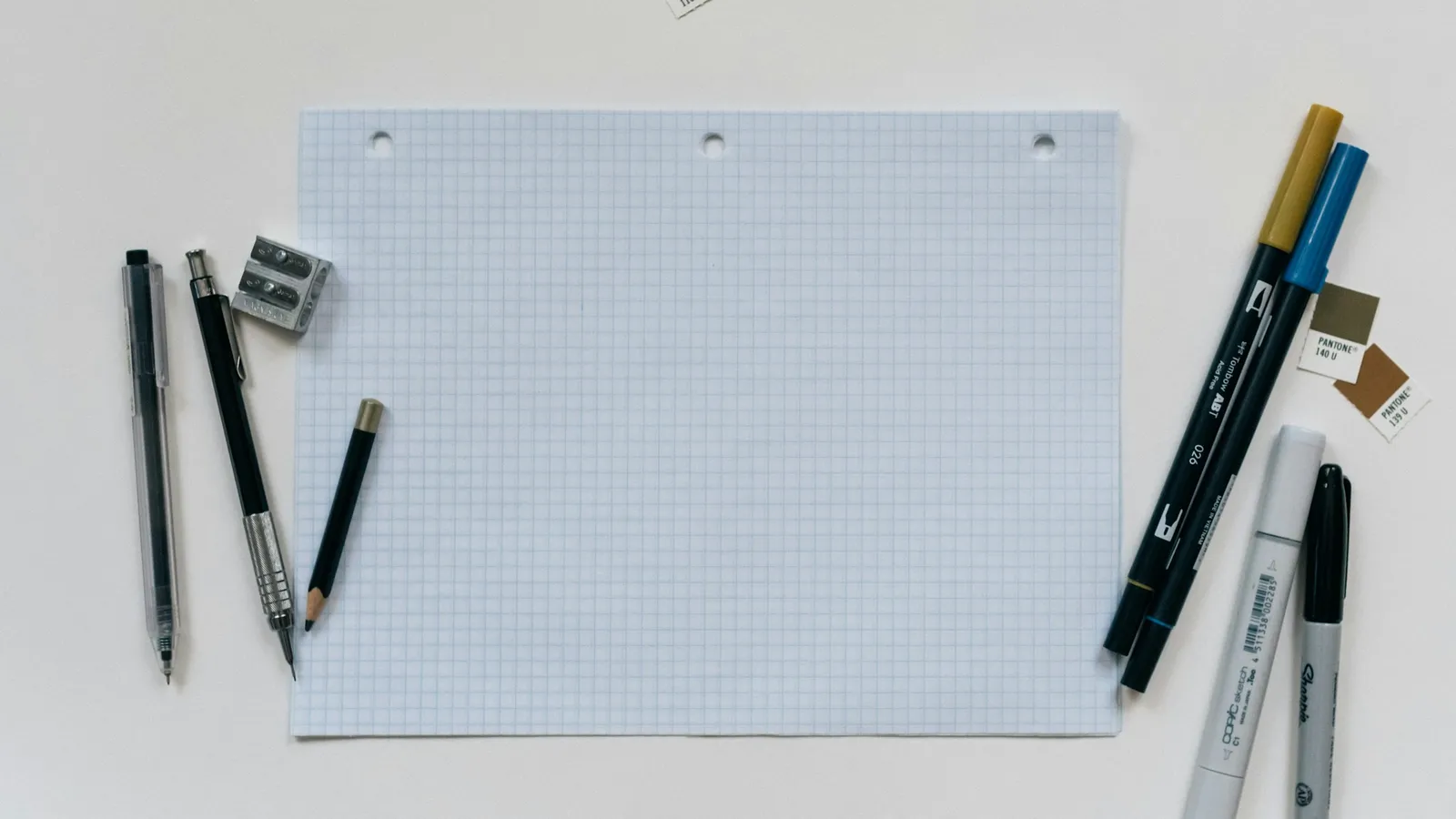 A sheet of grid paper with pens beside it