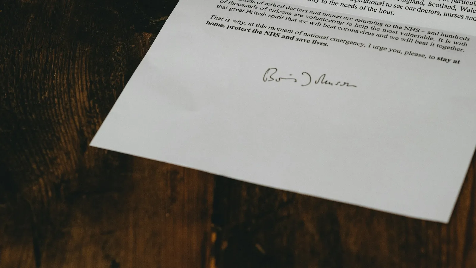 A signed letter lying on a dark wooden table