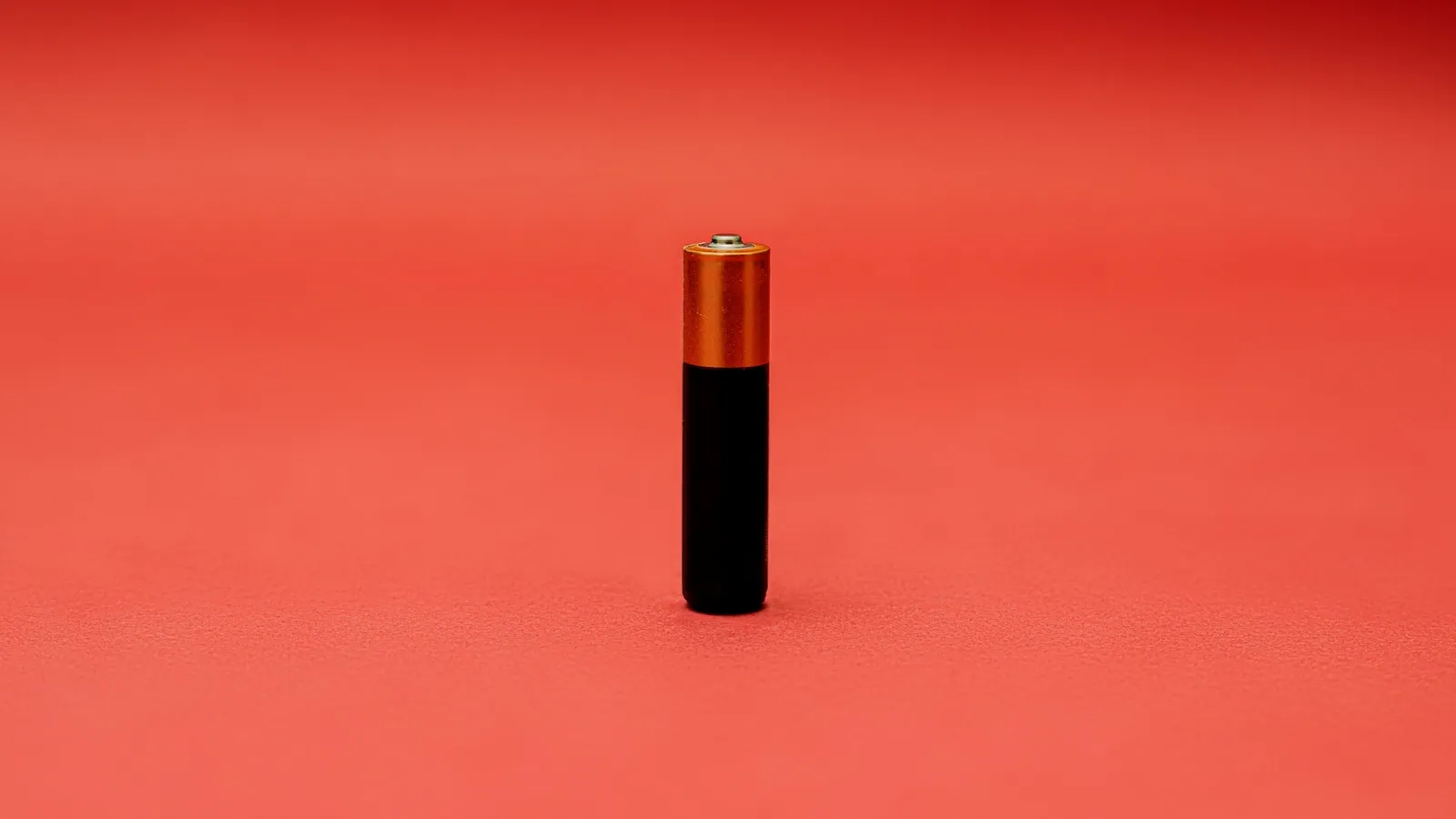 A single small battery on a red background