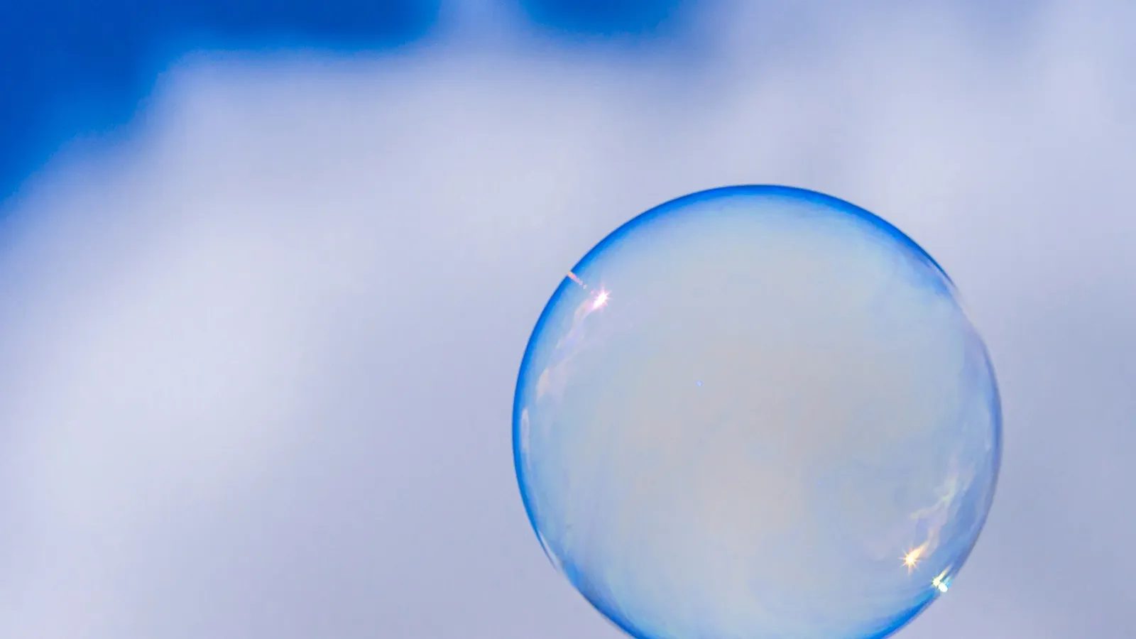 A single soap bubble floating against a blue sky