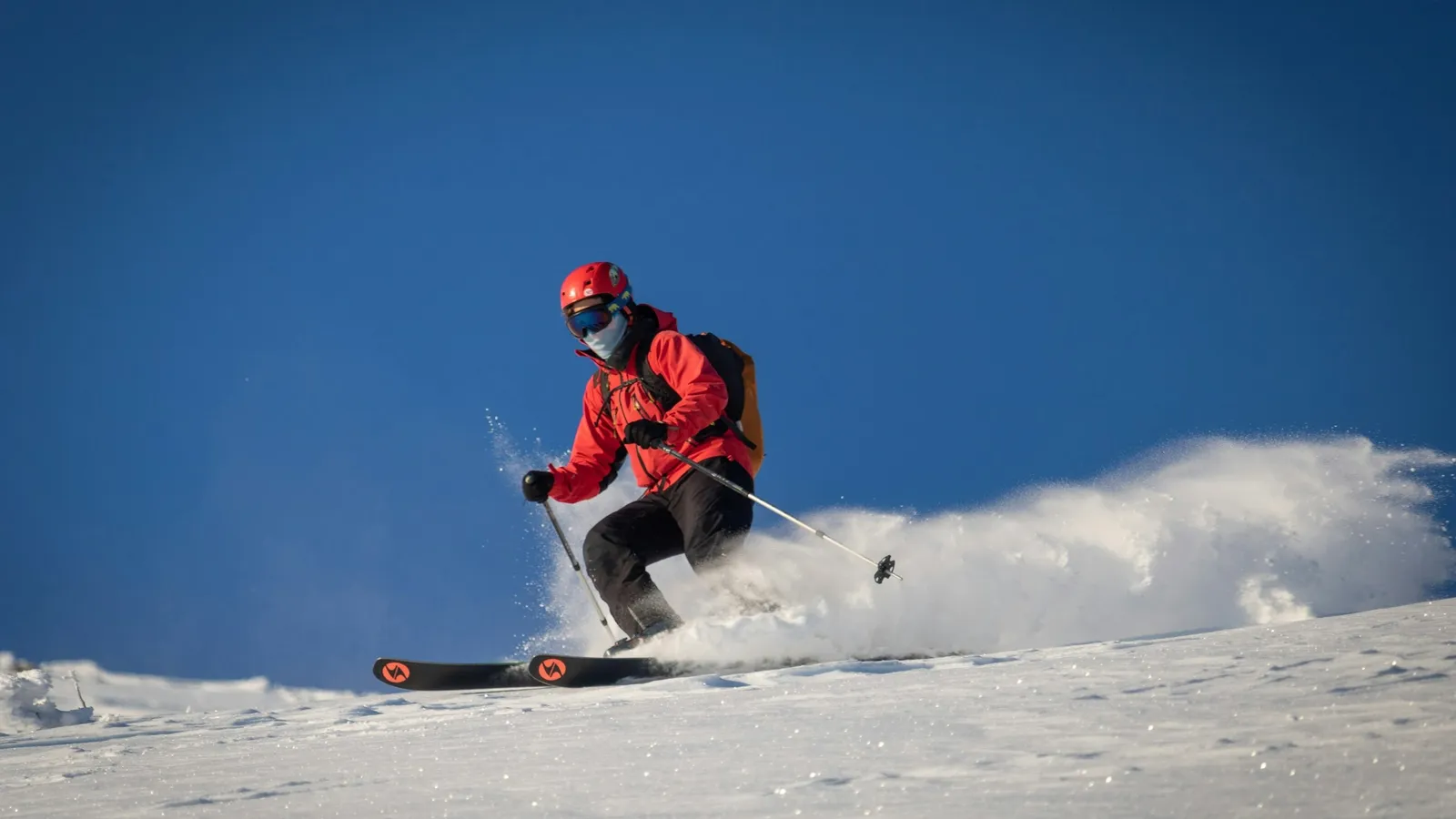 A skier kicking up snow on a steep slope
