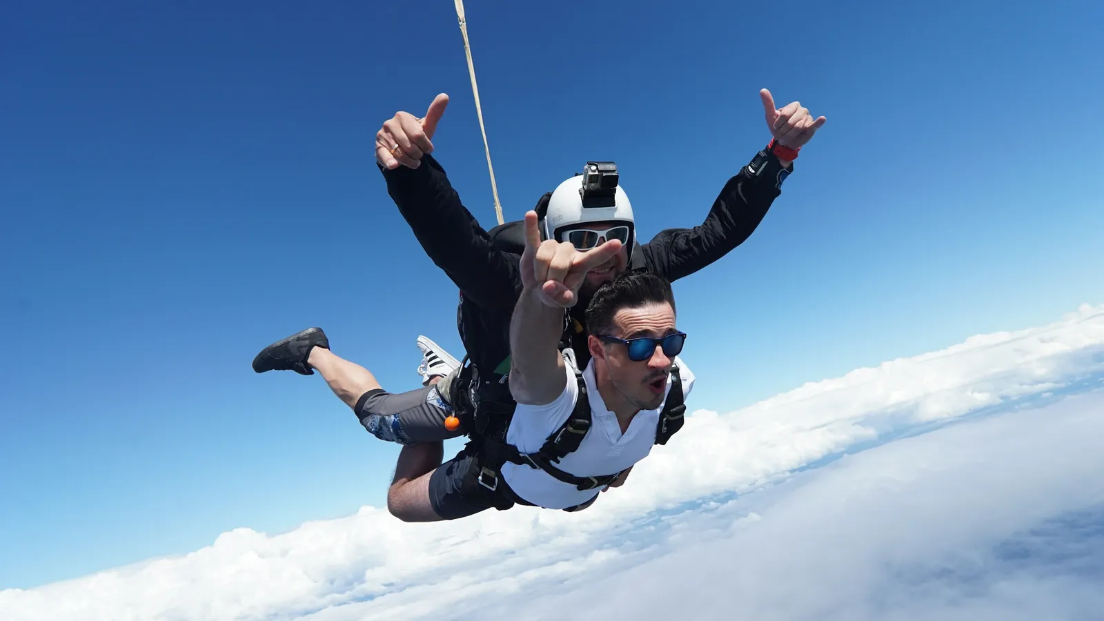 A skydiver falling with arms spread above clouds
