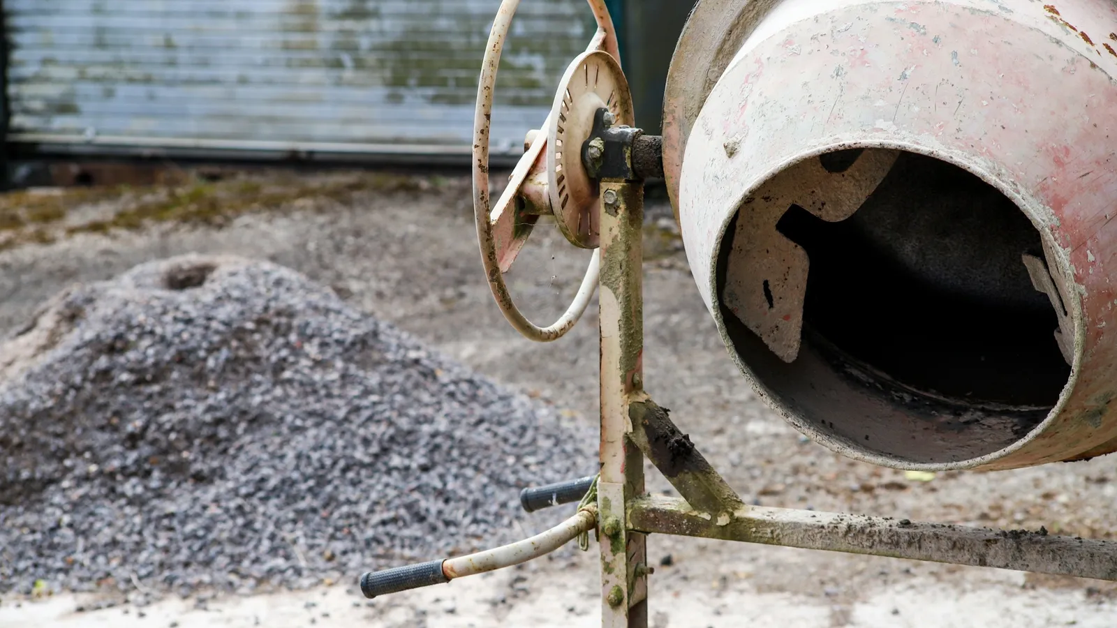 A small cement mixer beside a pile of gravel