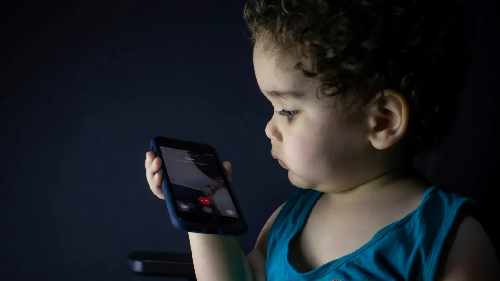 A small child looking intently at a smartphone