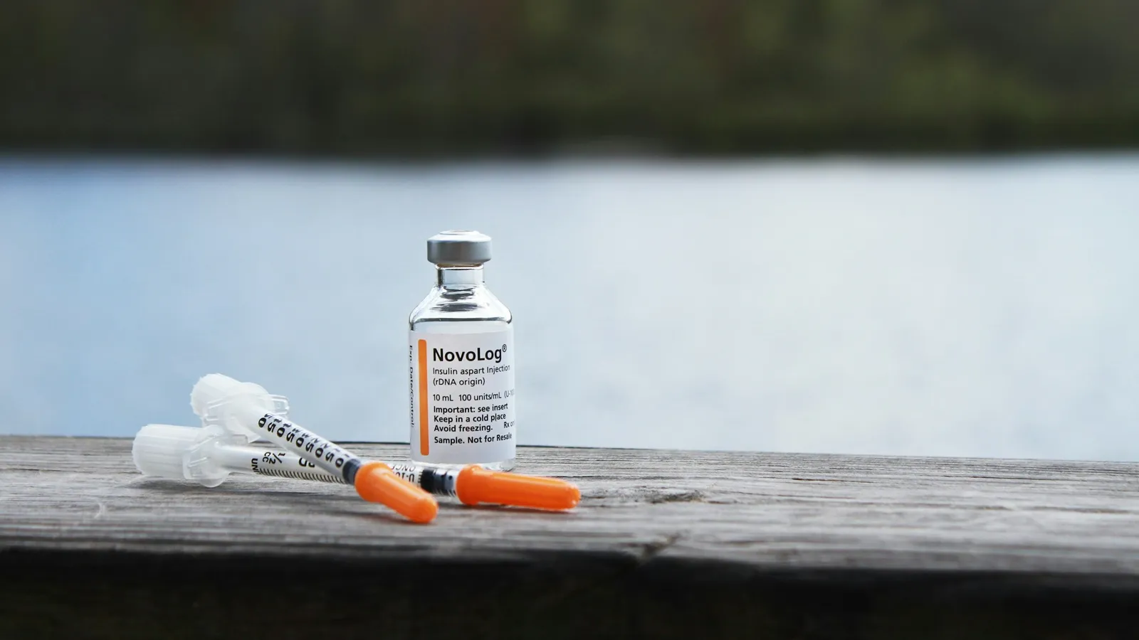 A small medicine vial and syringe on a wooden surface