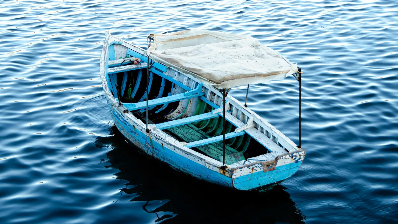 A small wooden boat with a canopy floating on blue water