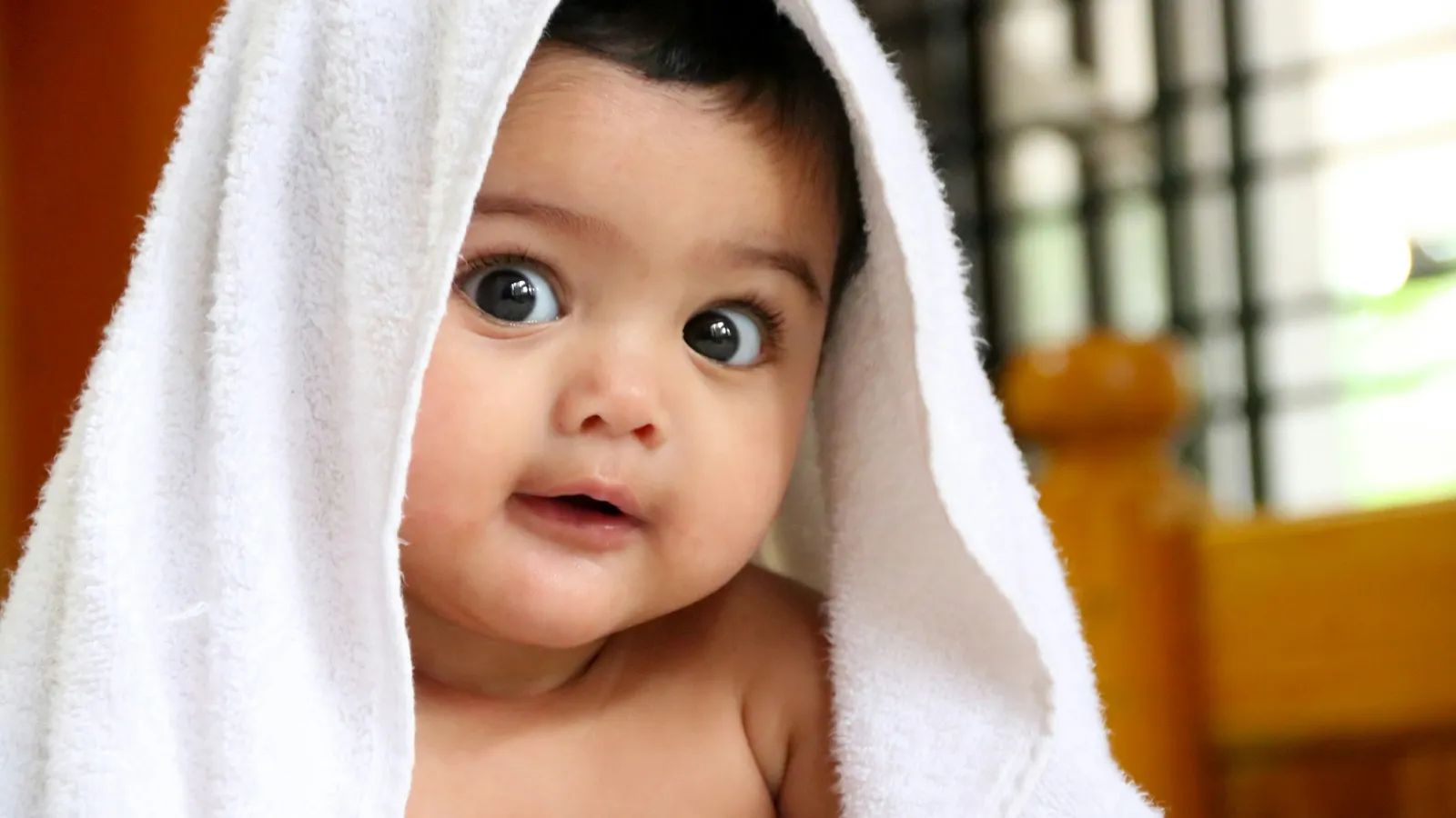 A smiling baby wrapped in a white towel
