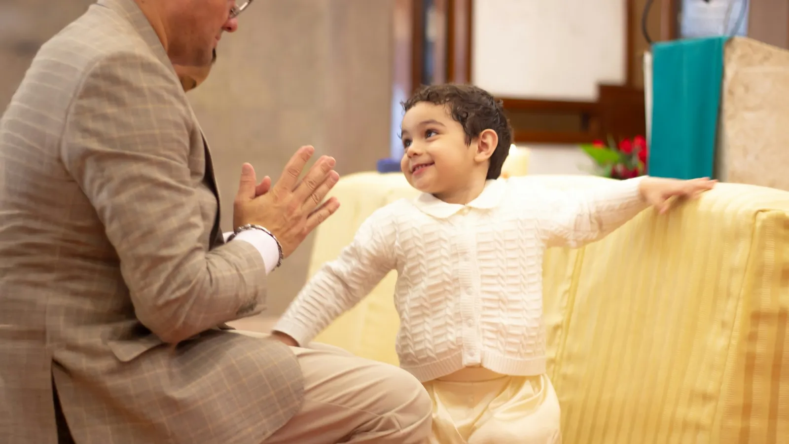 A smiling man and a young girl giving each other a high five at home
