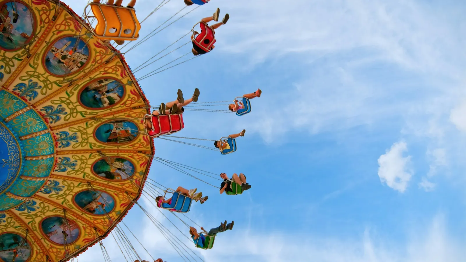 A spinning swing ride seen from below against the sky