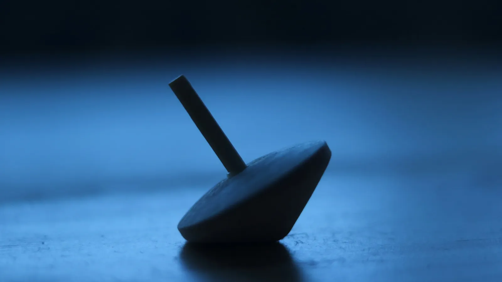 A spinning top tilted on a blue surface
