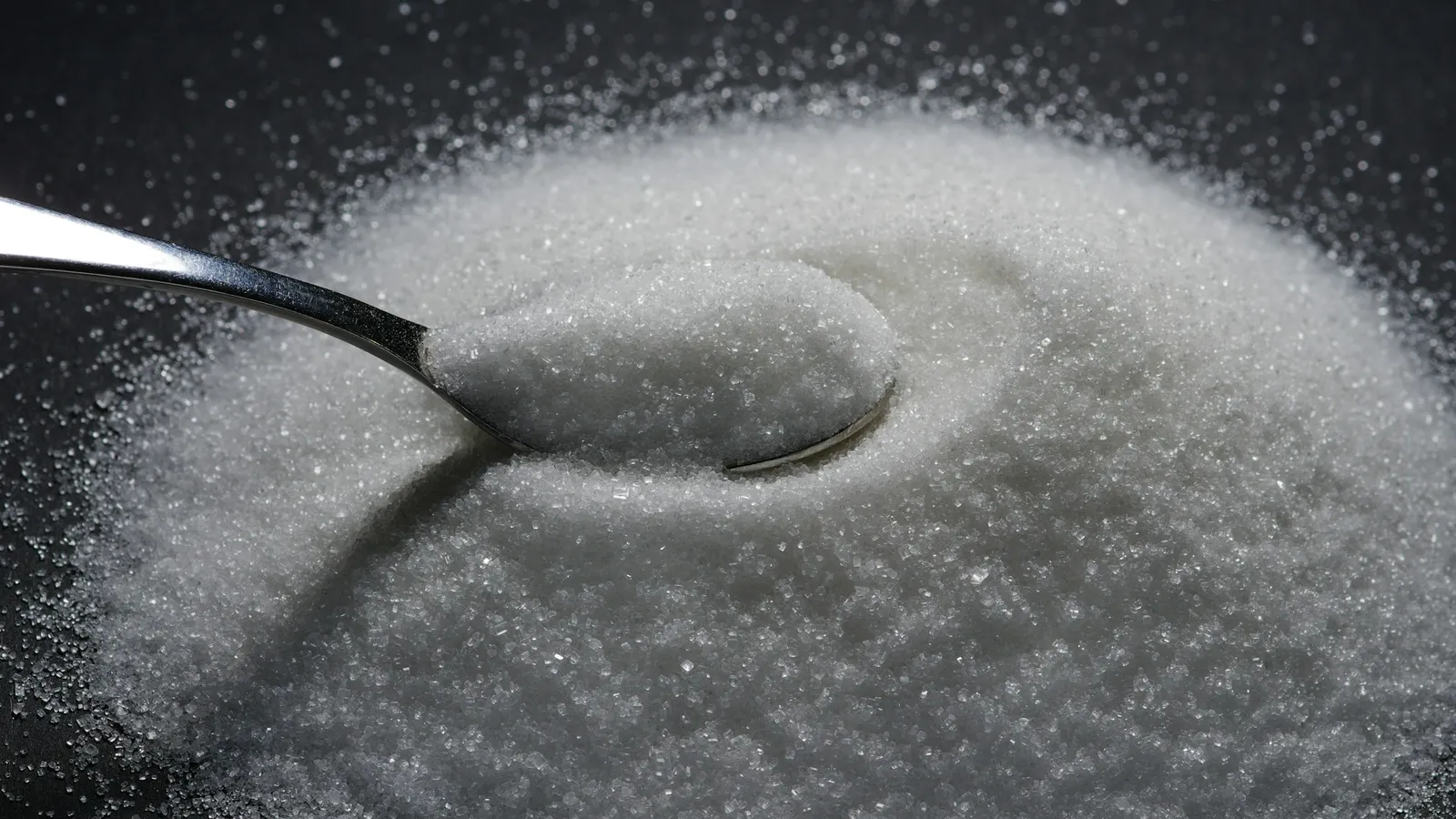 A spoon resting in a heap of white crystals
