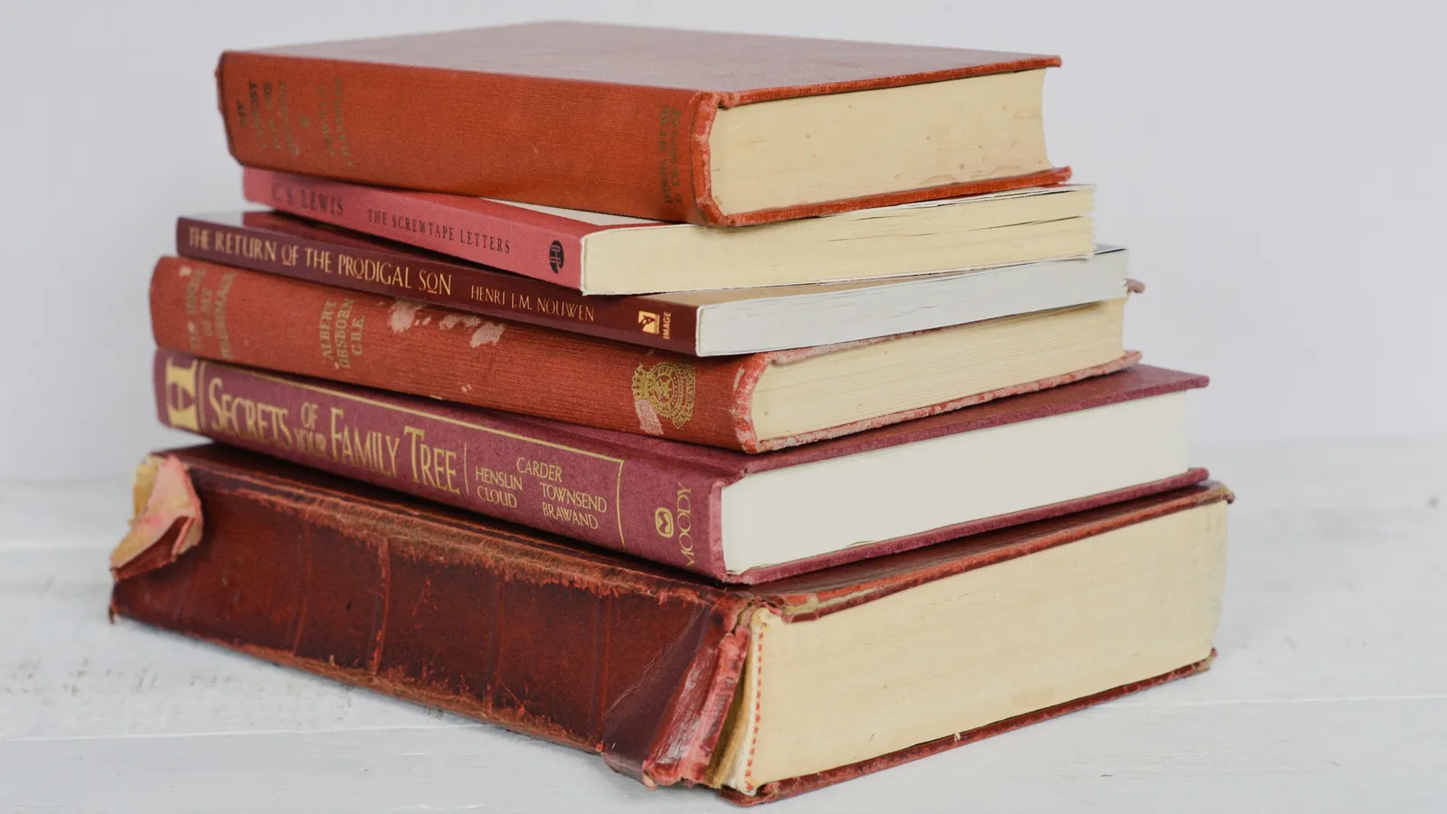 A stack of hardback textbooks on a white table
