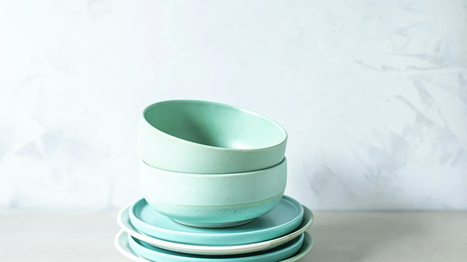 A stack of pale green bowls on a white surface