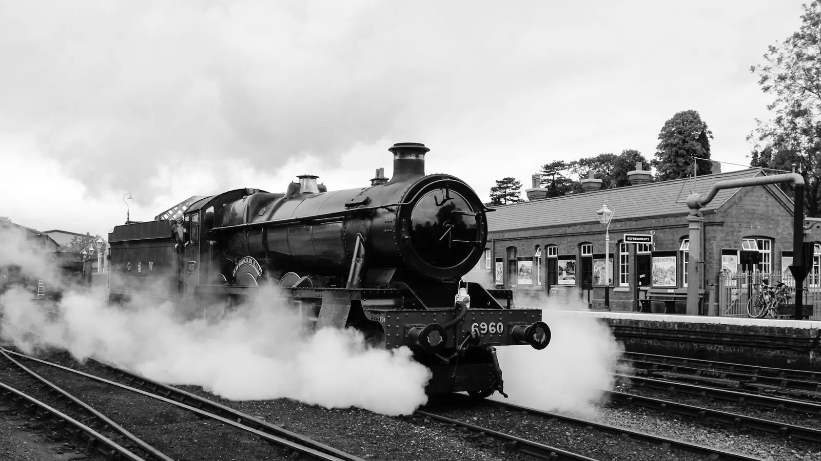 A steam locomotive puffing steam, in black and white