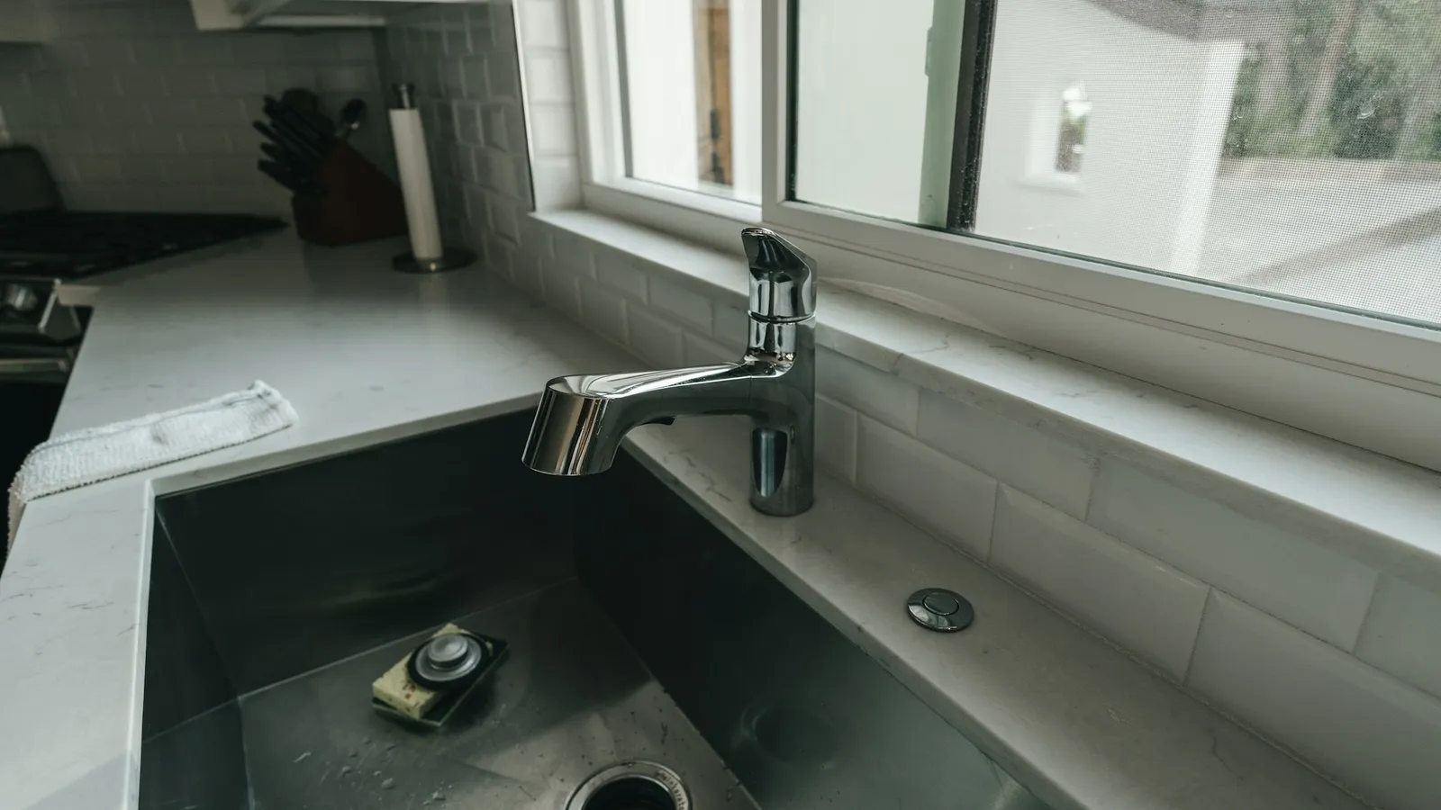 A steel kitchen sink beside a window
