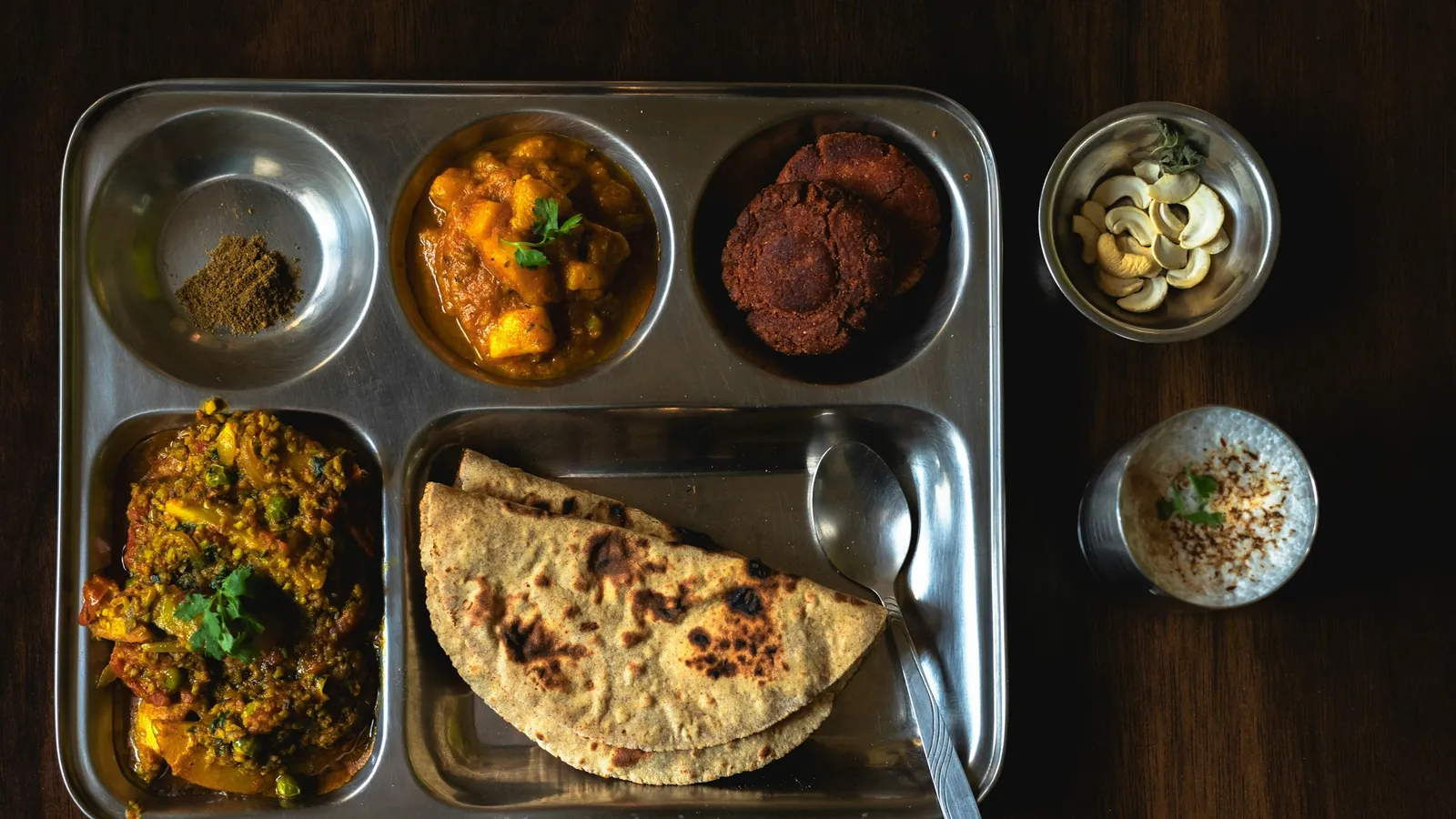 A steel thali tray with rice, dal, vegetables and roti