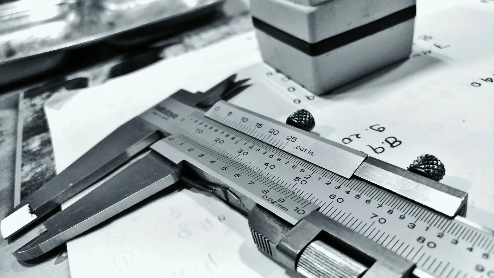 A steel vernier calliper resting on a metal workpiece