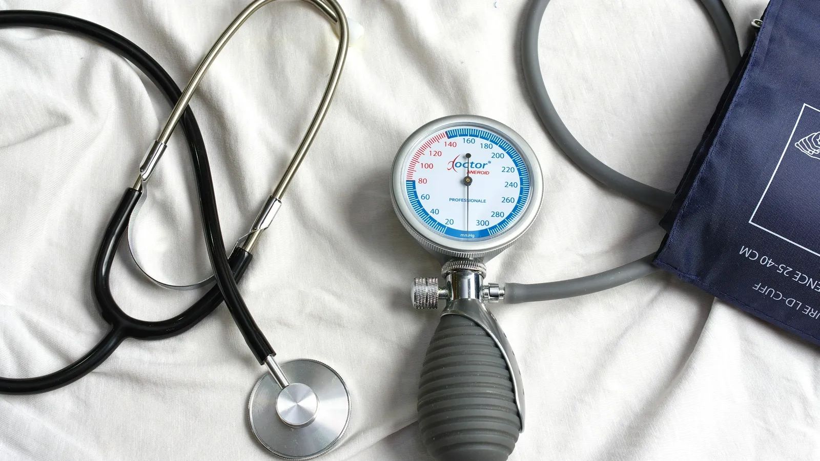 A stethoscope and blood pressure cuff on white cloth