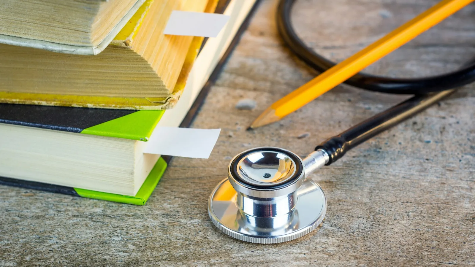A stethoscope and pencil beside a stack of books