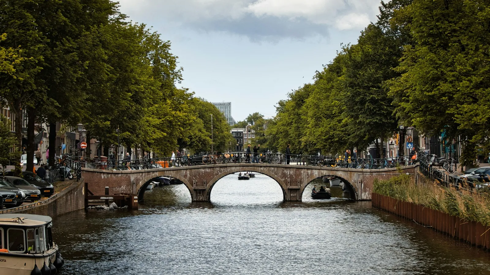 A stone bridge over a canal lined with trees