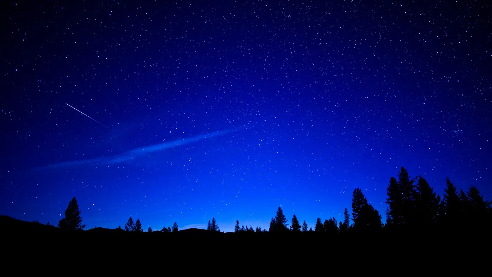 A streak of light across a starry night sky
