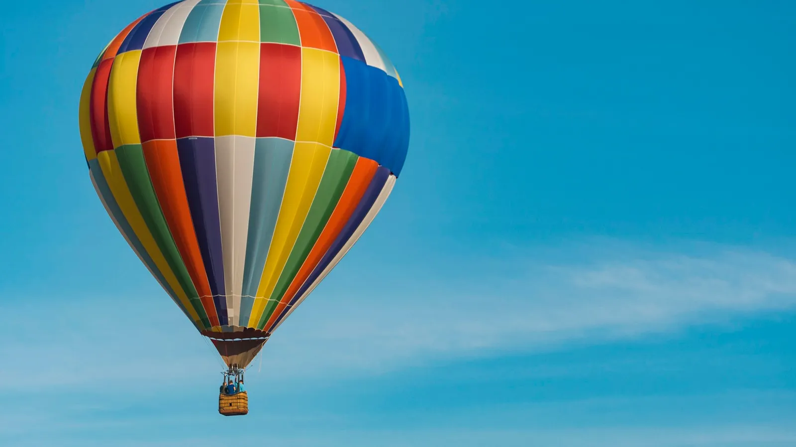A striped hot-air balloon floating against a blue sky