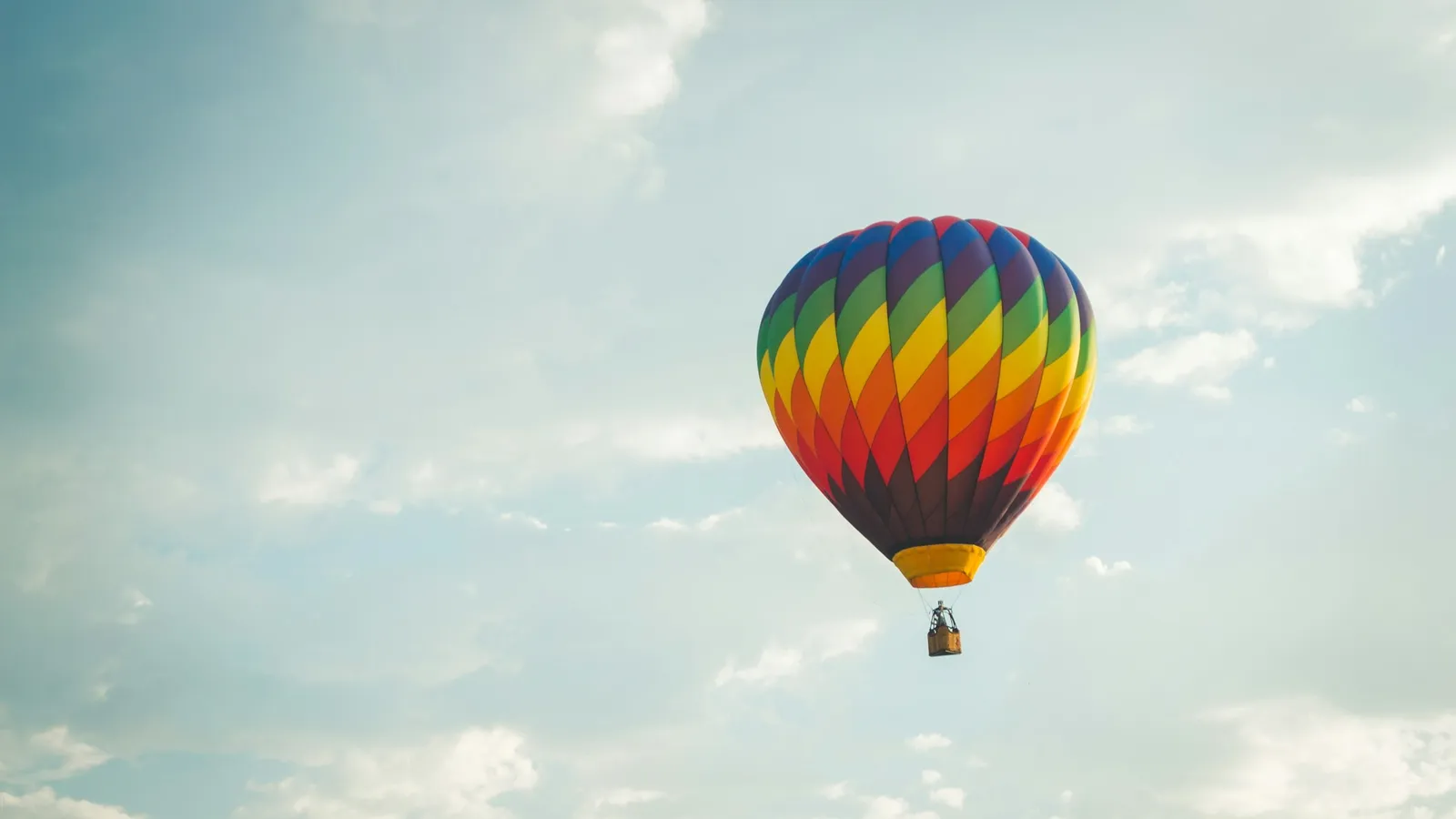 A striped hot air balloon in a cloudy sky