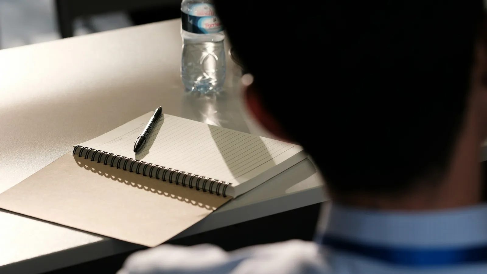 A student at a desk with an open notebook and pen