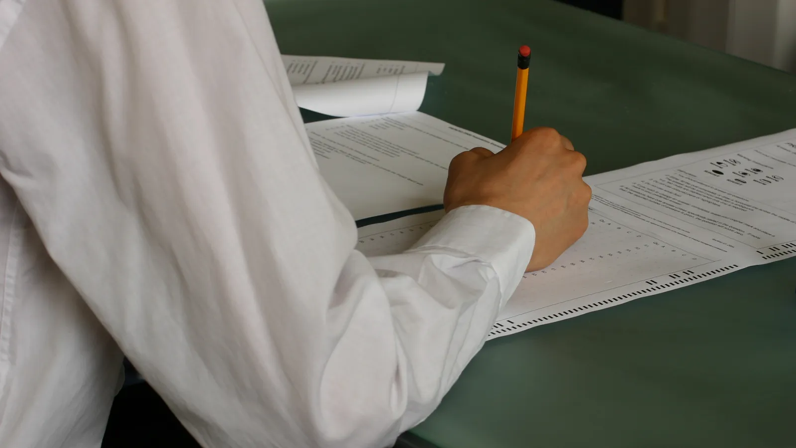 A student in a classroom writing an exam paper