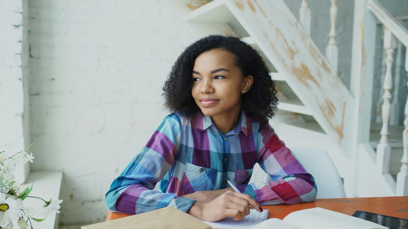A student pausing to think while writing at a desk