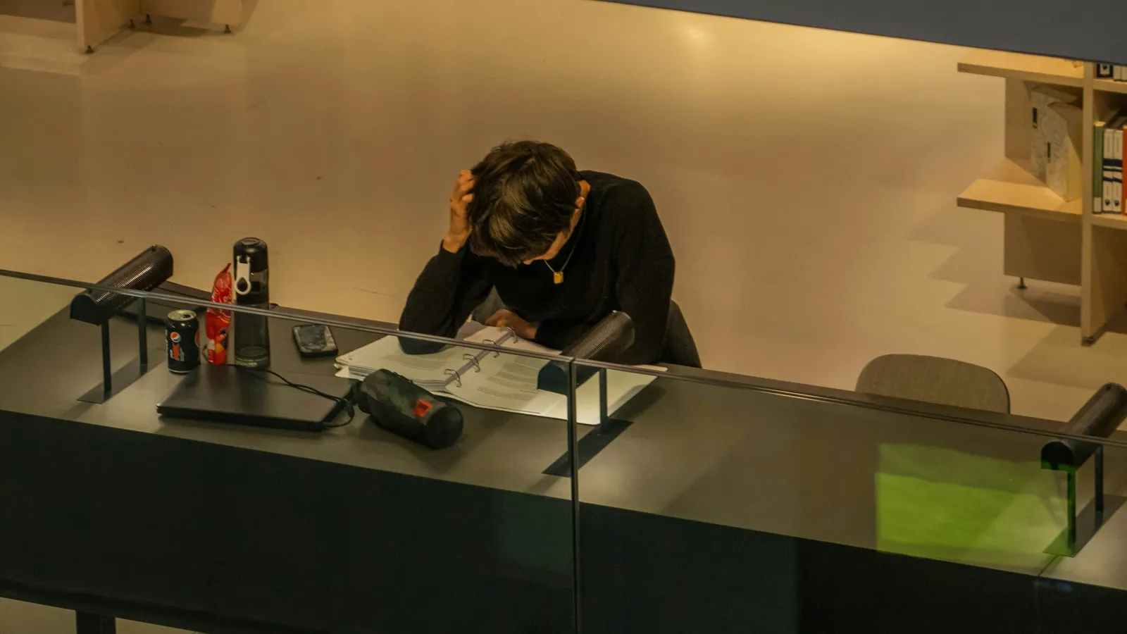 A student studying alone at a desk in a dim room