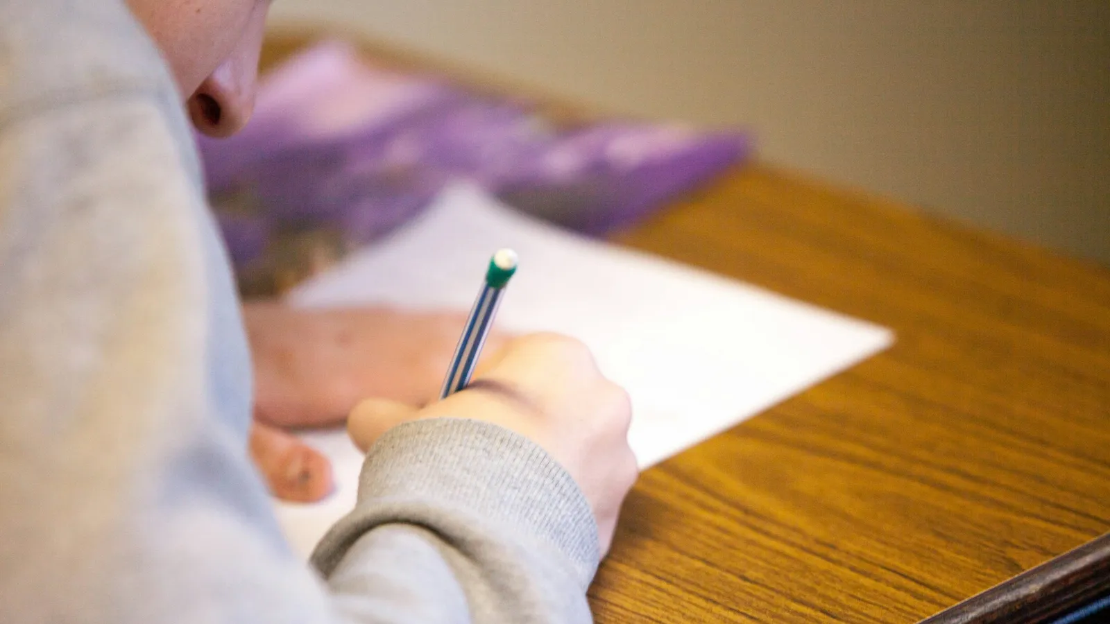 A student writing answers on an exam paper at a desk