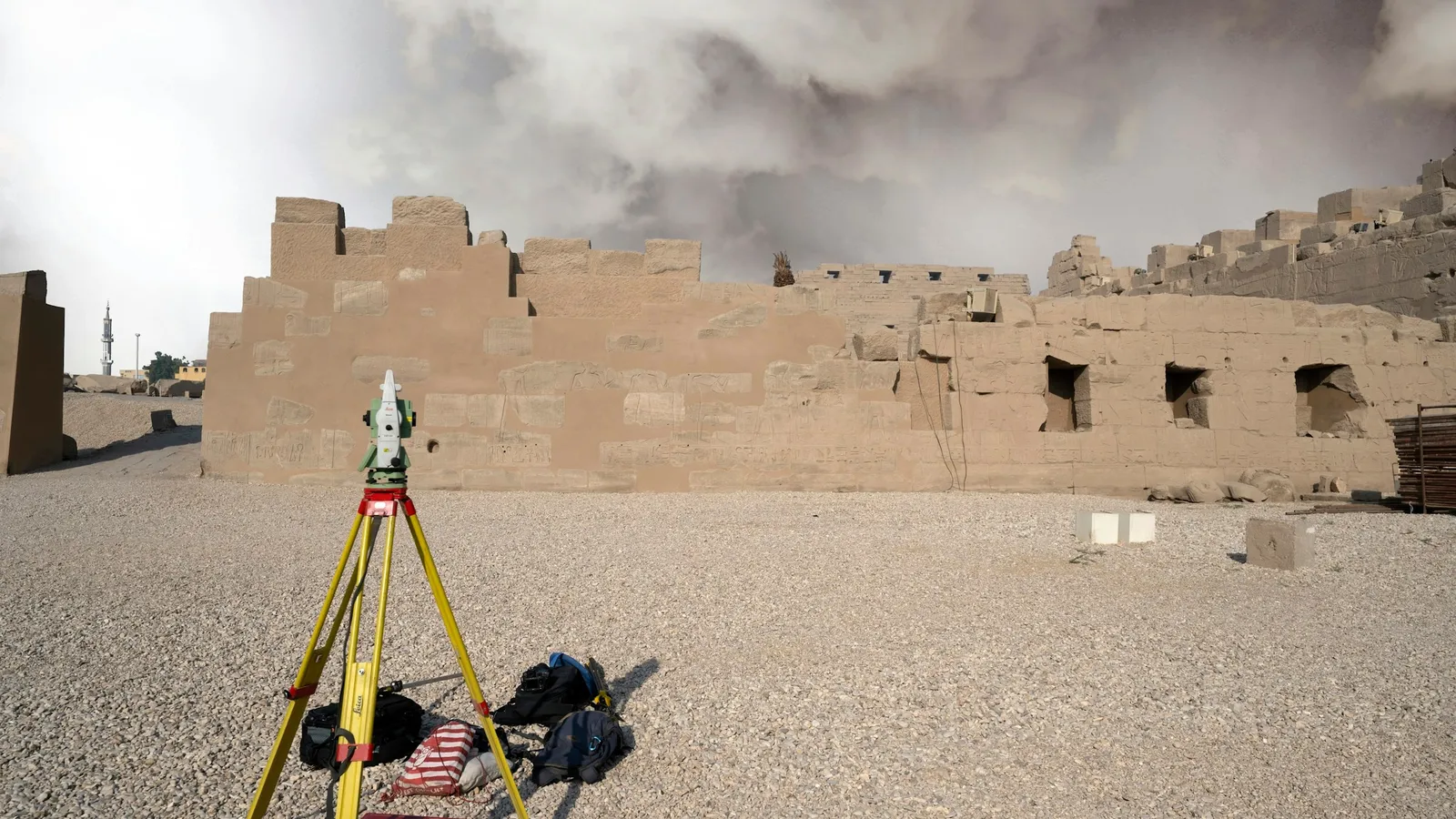 A surveying instrument on a tripod in a dusty landscape